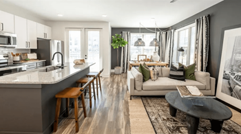 A modern kitchen with a bar stool and a dining area with a couch and a coffee table.